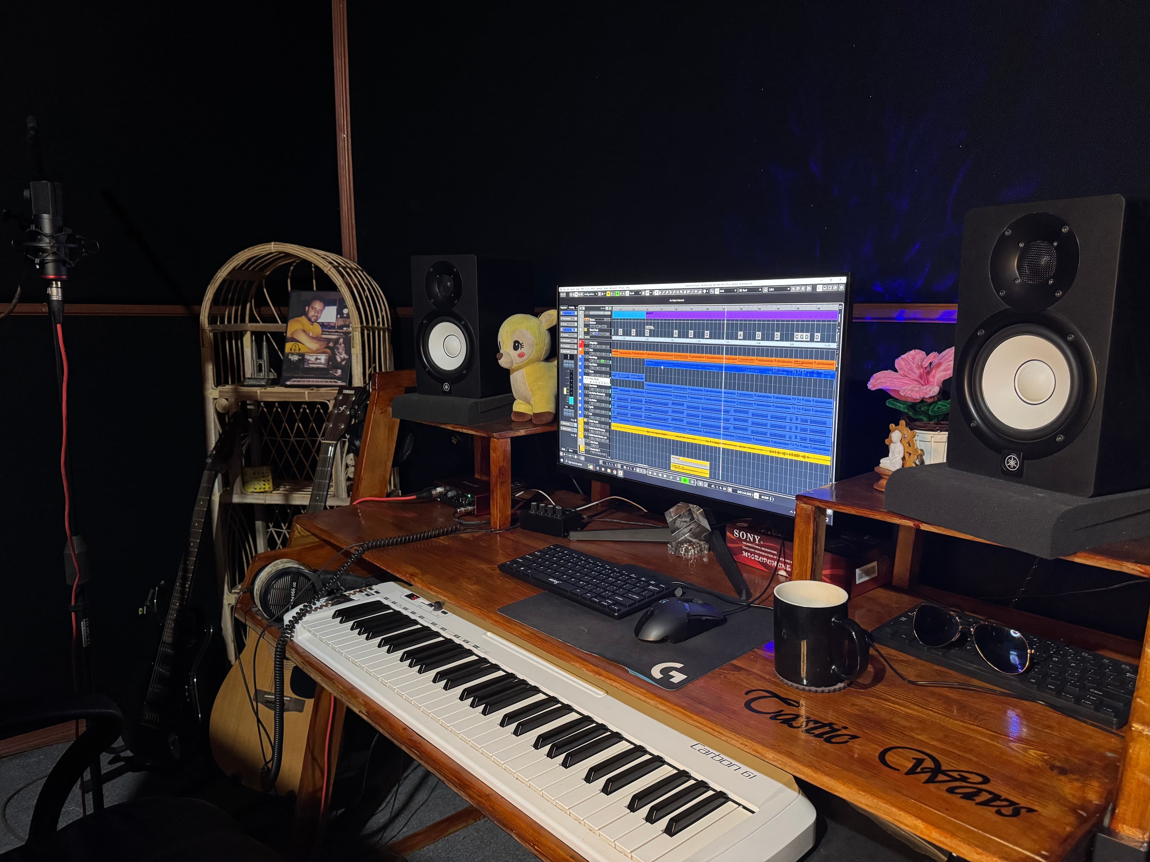 Close-up of the Tastic Wavs production desk with monitor speakers, computer display, and MIDI keyboard.